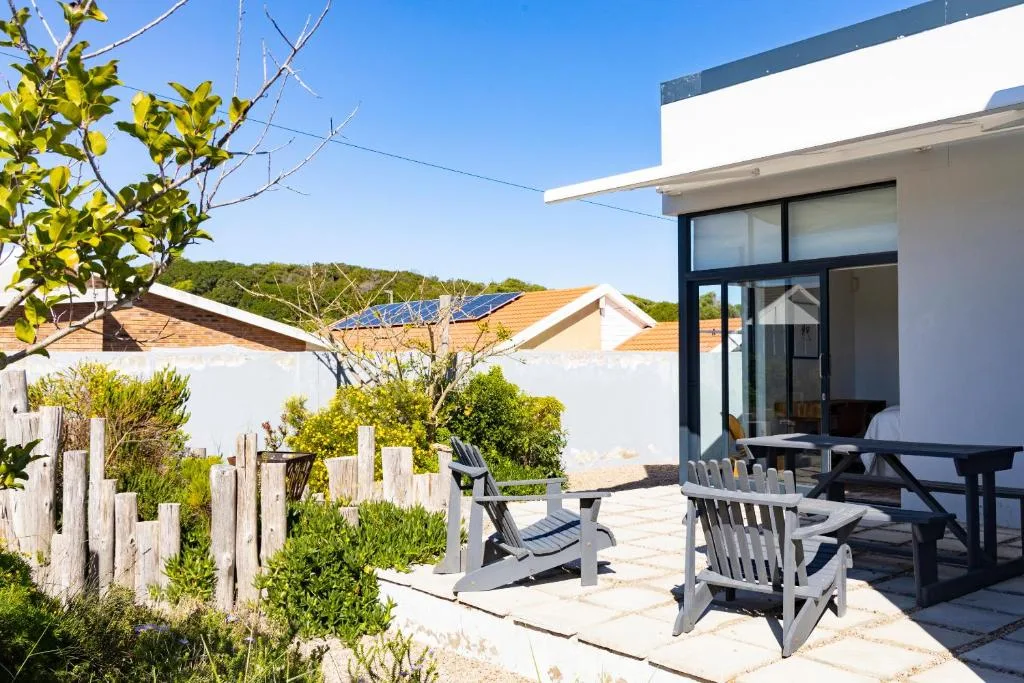 Outdoor patio with Adirondack chairs and dining table overlooking garden