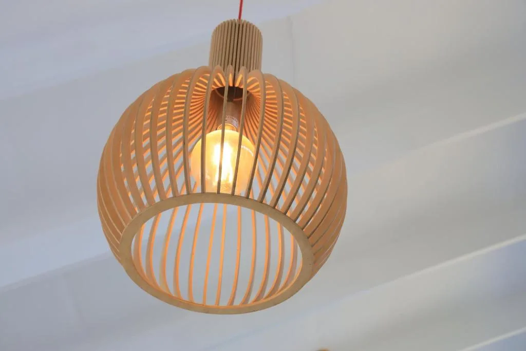 Wooden spherical pendant light fixture suspended from white ceiling