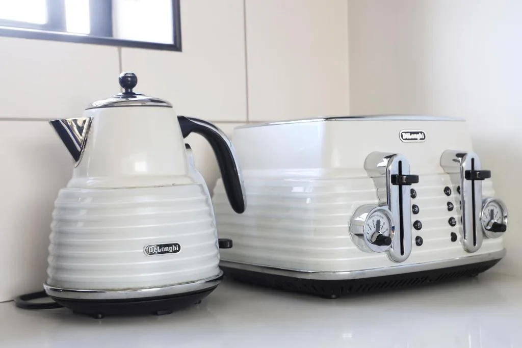 White DeLonghi kettle and four-slot toaster on kitchen counter
