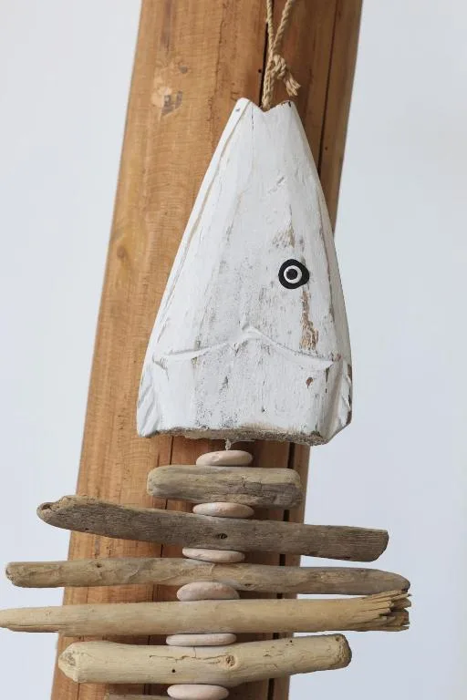 Rustic wooden wind chime with driftwood and white painted fish-shaped bell