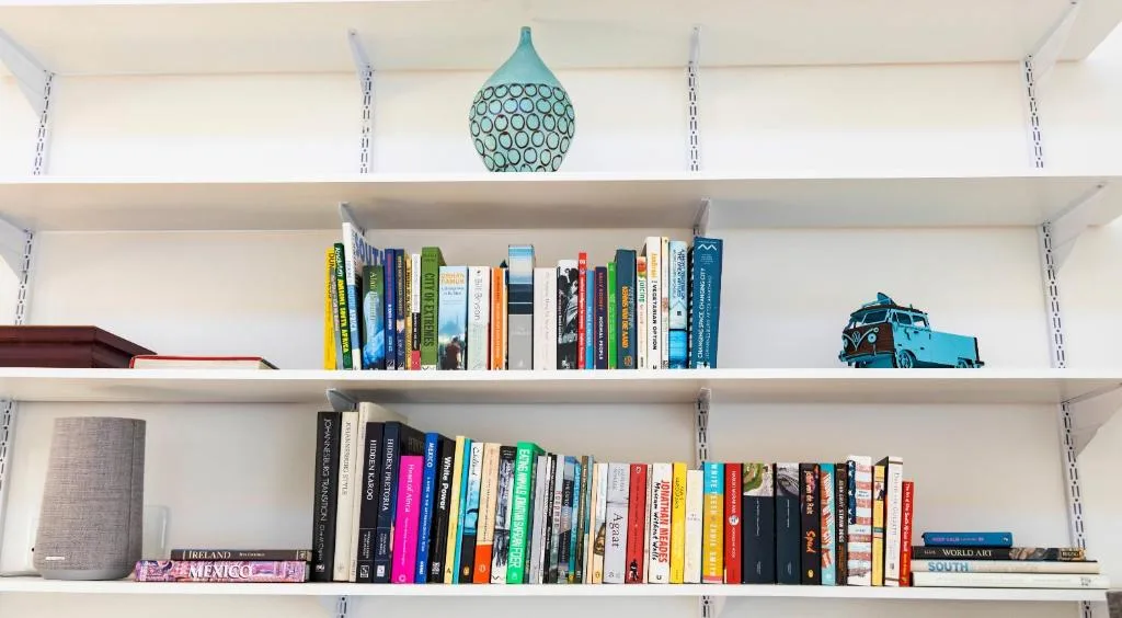 White shelving unit displaying books, decorative items, and travel memorabilia