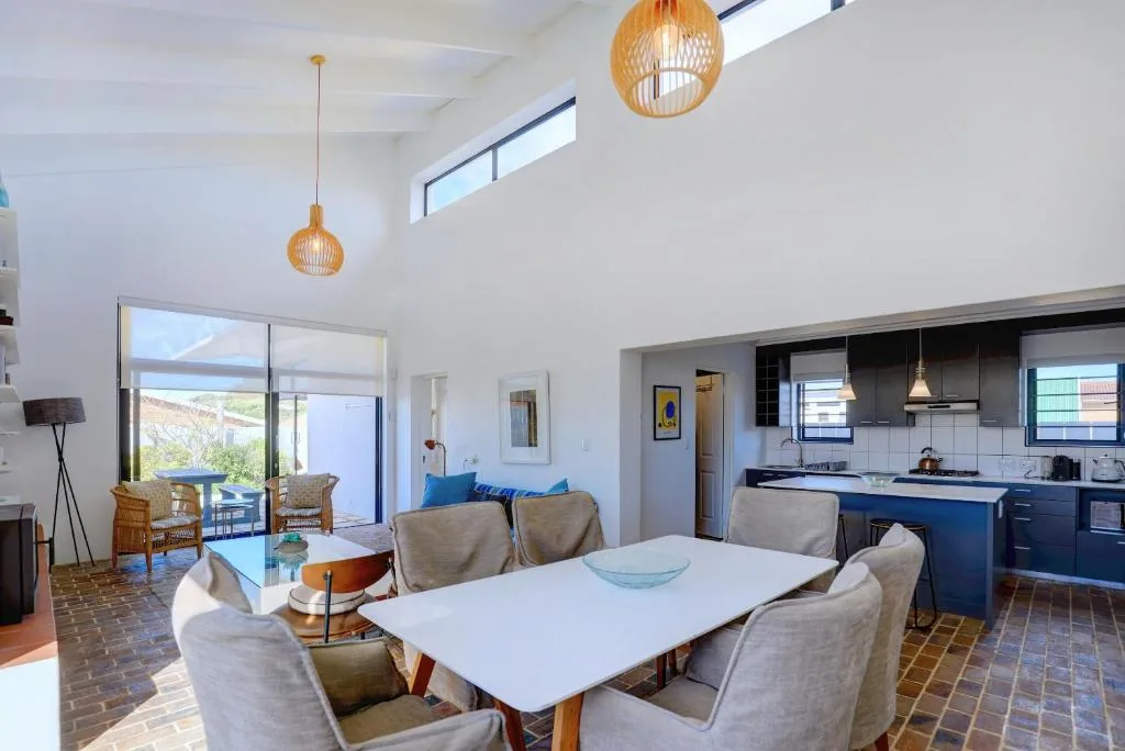 Modern dining area with white table, beige chairs, and woven pendant lights