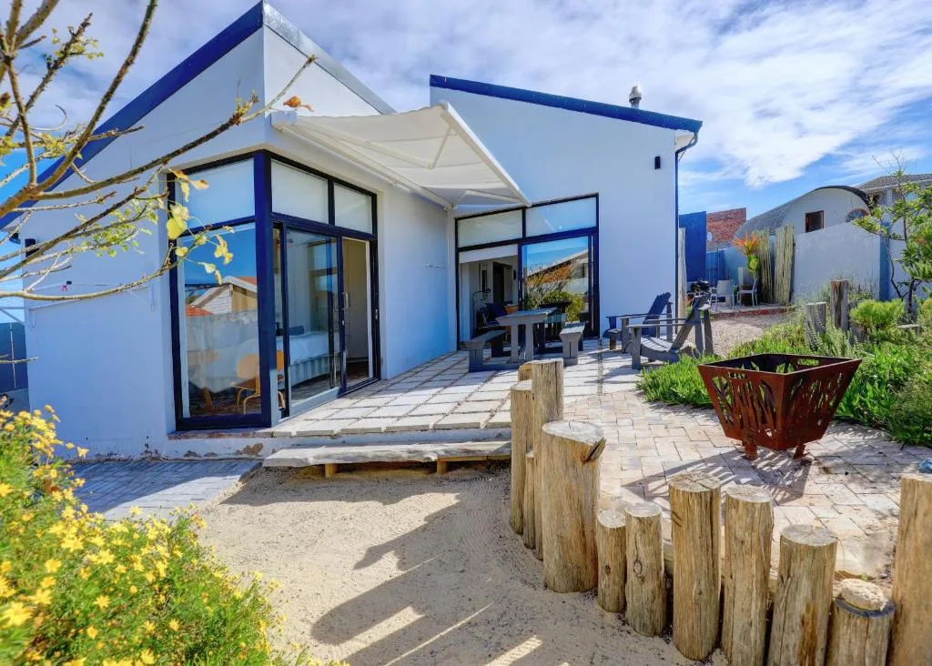 Modern blue and white cottage with retracted awning and sandy garden path