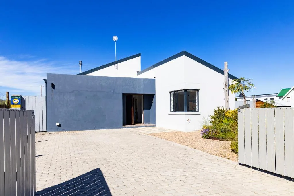 Modern white and grey house with paved driveway and white fencing