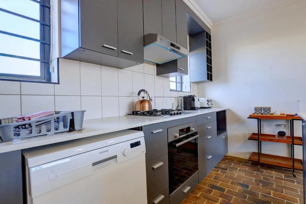 Modern kitchen with dark cabinetry, stainless steel appliances, and tiled backsplash