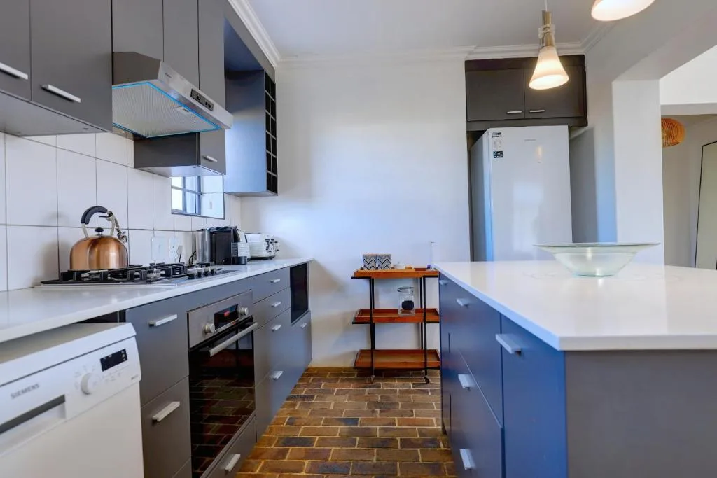 Modern kitchen with dark cabinetry, white counters, and stainless steel appliances