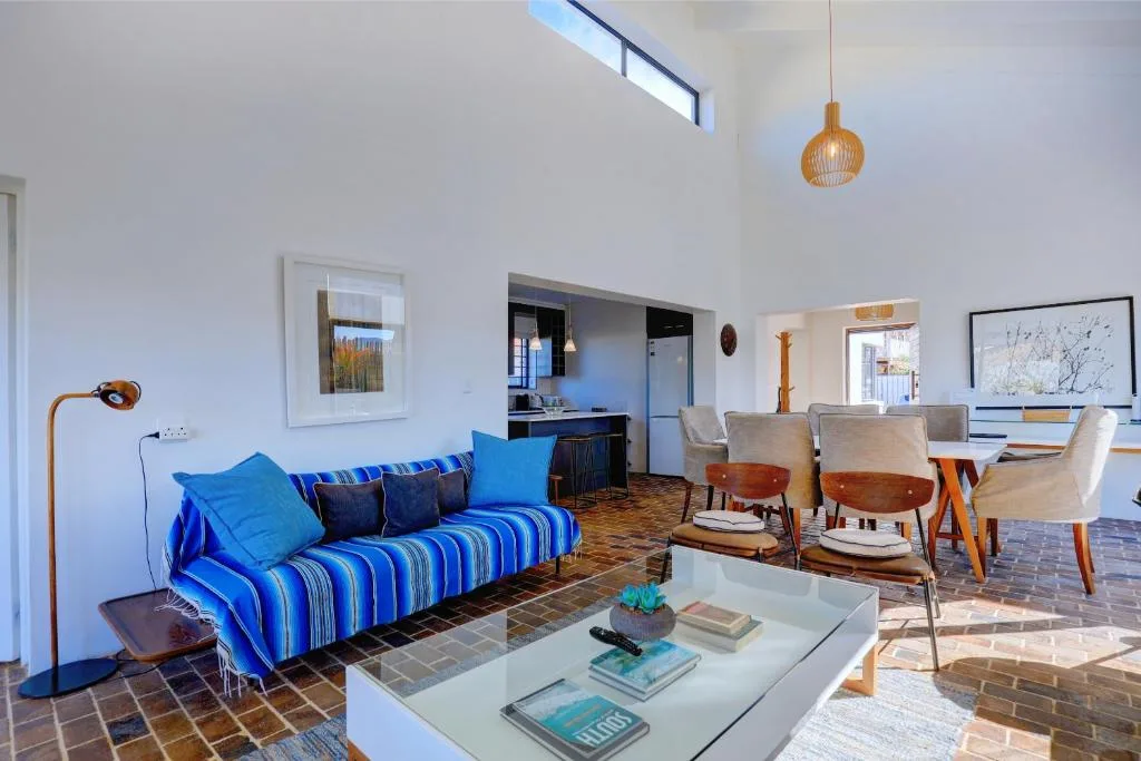 Modern lounge with blue striped sofa, dining area, and open-plan kitchen visible