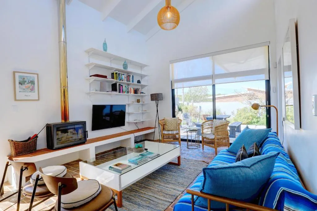 Bright open-plan lounge with blue striped sofa, TV, and scenic landscape views