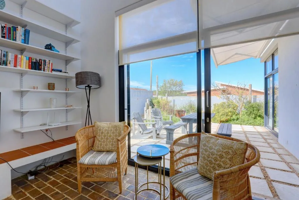 Bright lounge with wicker chairs, bookshelves, and deck access with mountain views