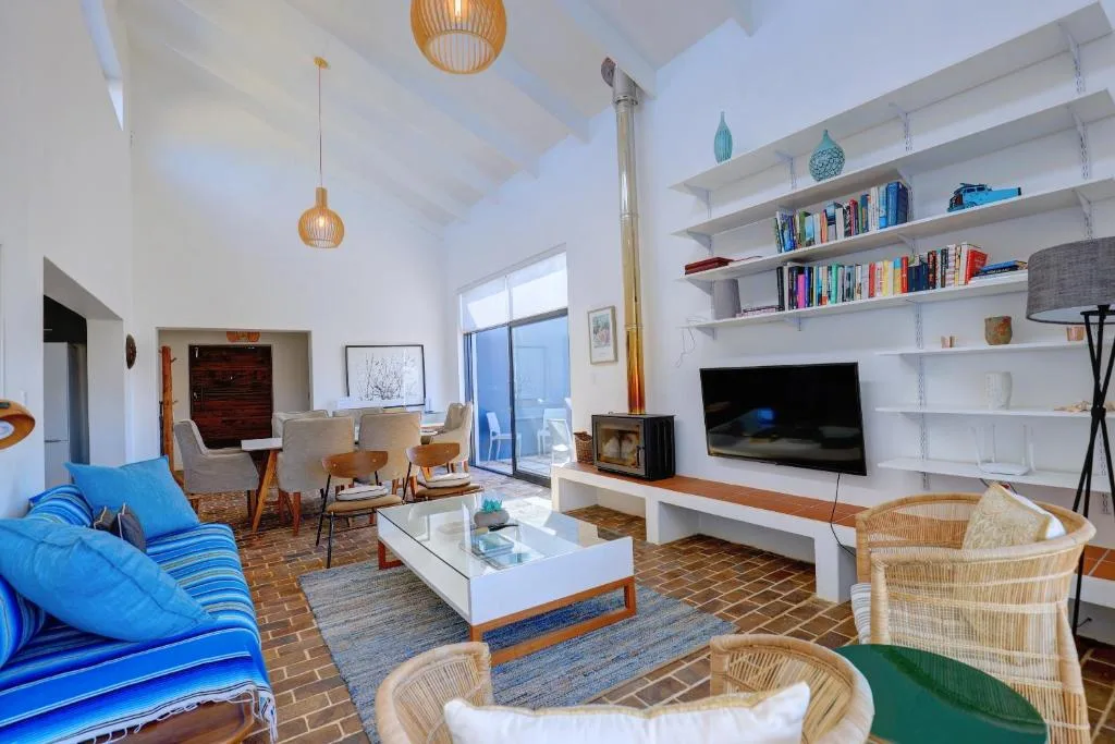 Bright open-plan lounge with blue sofa, TV, bookshelves, and modern decor