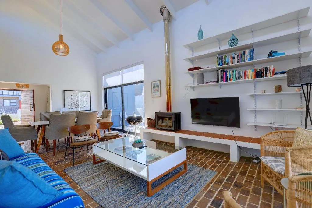 Open-plan lounge with blue sofa, fireplace, and bookshelves overlooking gardens