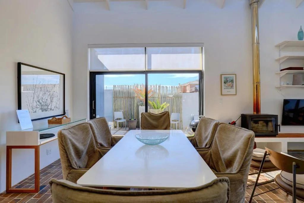Modern lounge with dining table, upholstered chairs, and ocean view