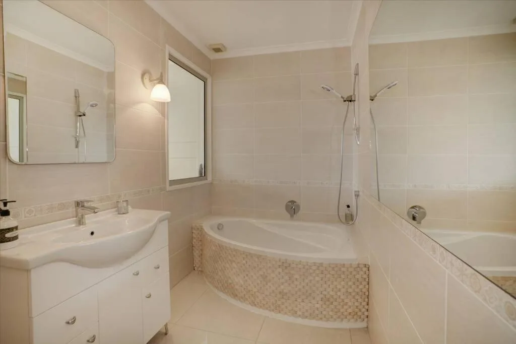 Modern bathroom with corner bath, shower, vanity and large mirror