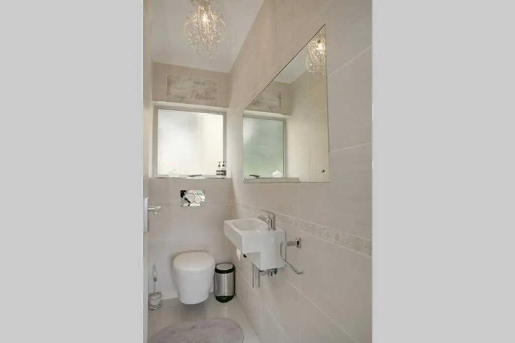 Clean modern bathroom with white vanity, toilet, and large mirrors