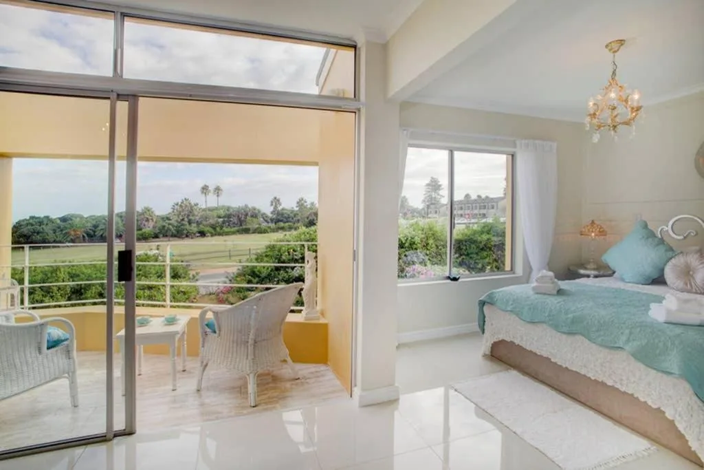 Bright bedroom with turquoise bedding overlooking lush green gardens and distant landscape