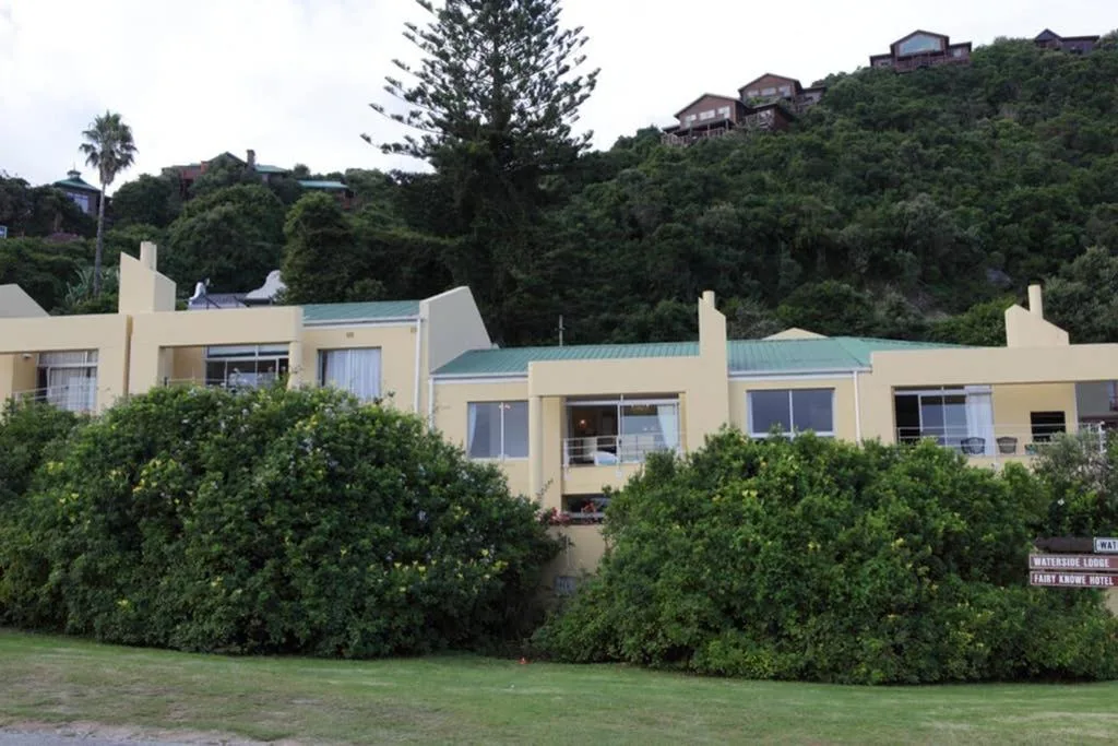 Cream-colored apartment building with turquoise roof nestled in lush green hillside