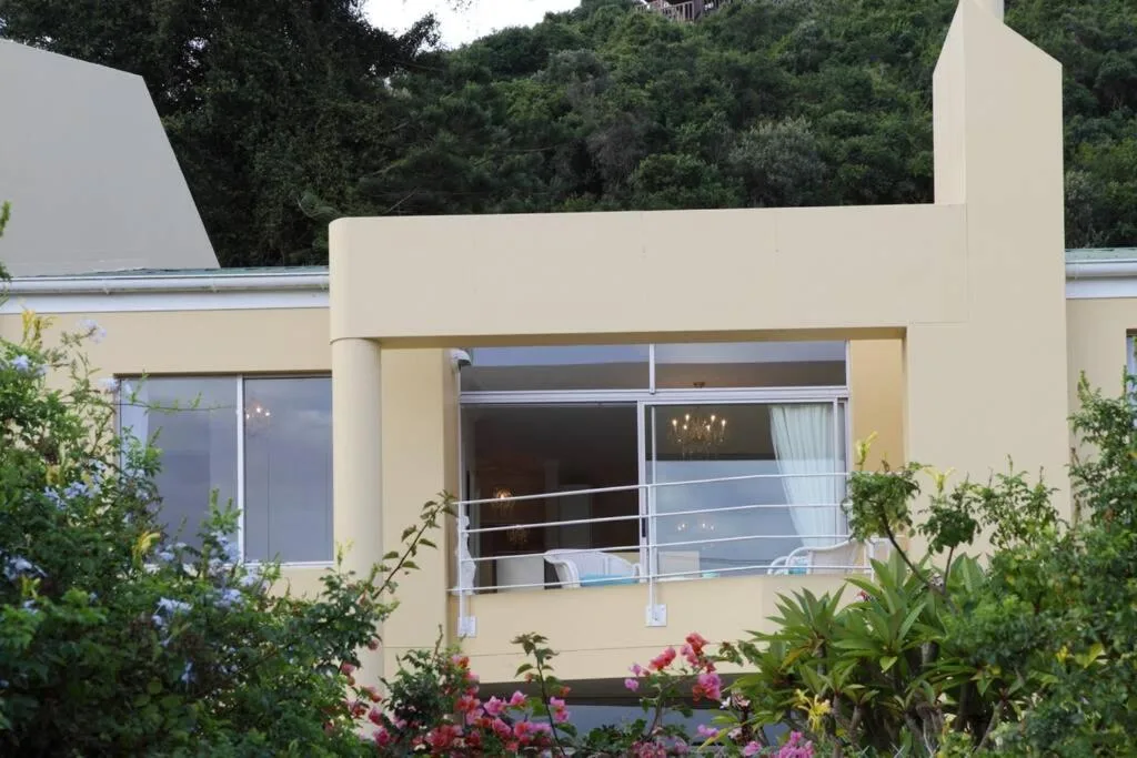 Modern cream apartment facade with large windows and flowering garden beds