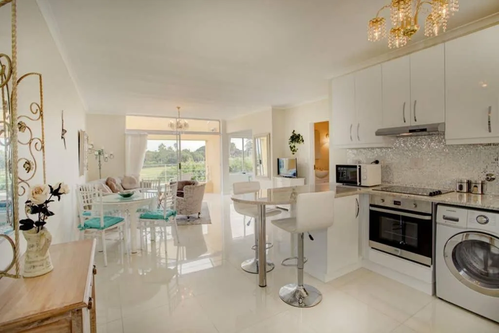 Modern white kitchen with stainless steel appliances and breakfast bar seating
