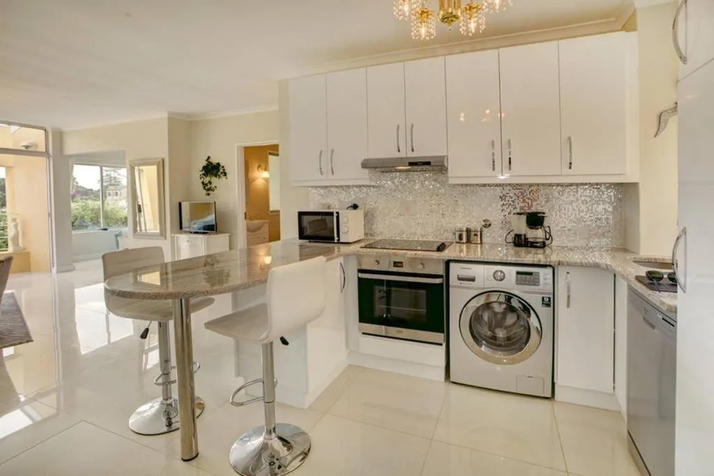 Modern white kitchen with stainless steel appliances and granite countertop