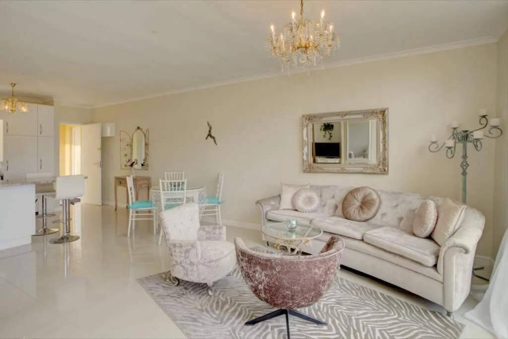 Elegant lounge with cream sofa, decorative pillows, and crystal chandelier