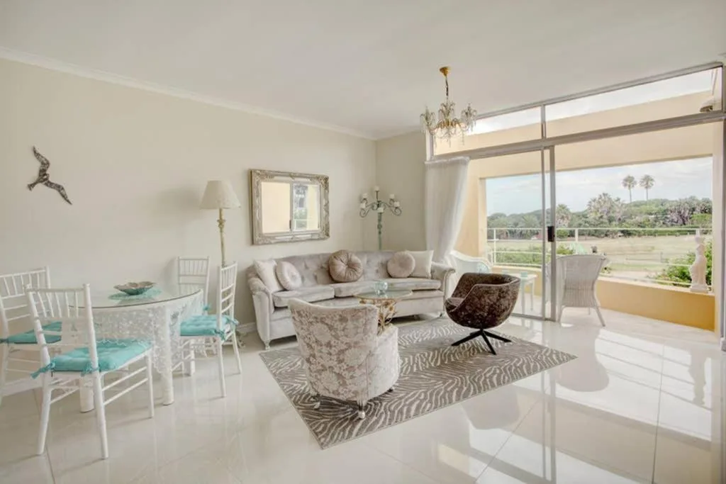 Bright lounge with sofa, armchair, and panoramic views of garden landscapes