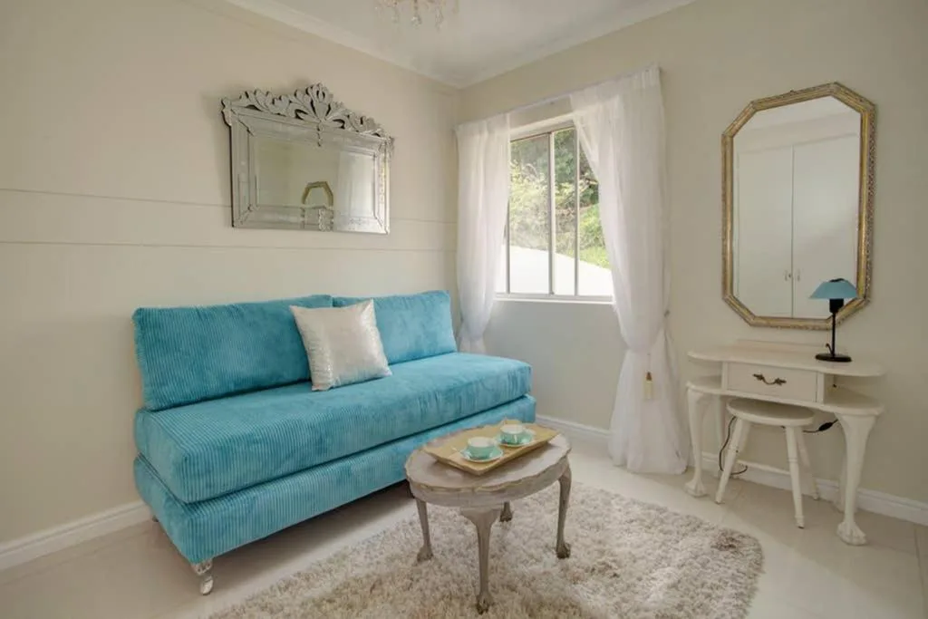 Bright lounge with turquoise sofa, vanity desk, and garden view