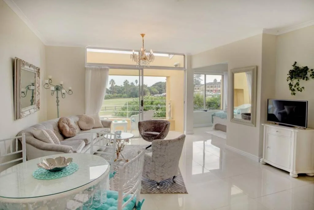 Bright lounge with sofa, elegant chairs, TV, and expansive garden views