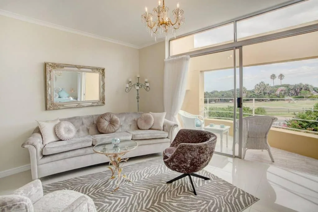 Elegant lounge with cream sofa, decorative mirror, and scenic garden views through sliding doors