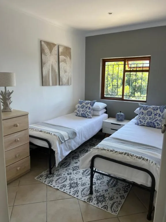 Twin bedroom with white linens, blue patterned pillows, and garden views