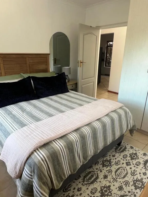 Spacious bedroom with striped bedding, wooden headboard, and modern mirror