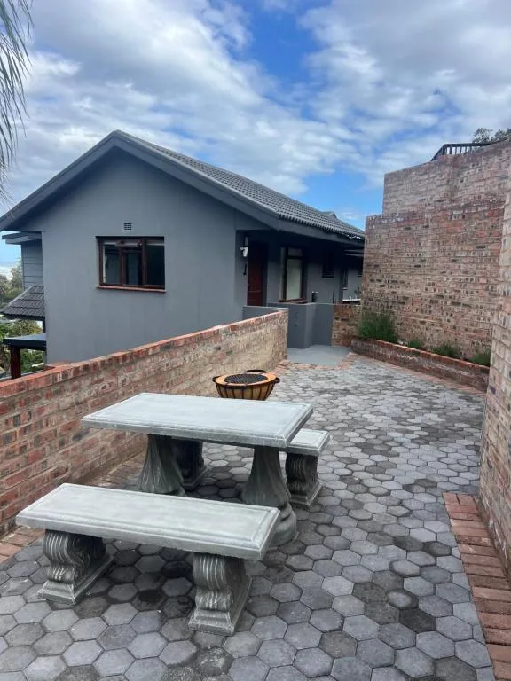 Outdoor patio with stone table, benches, and fire pit near modern home