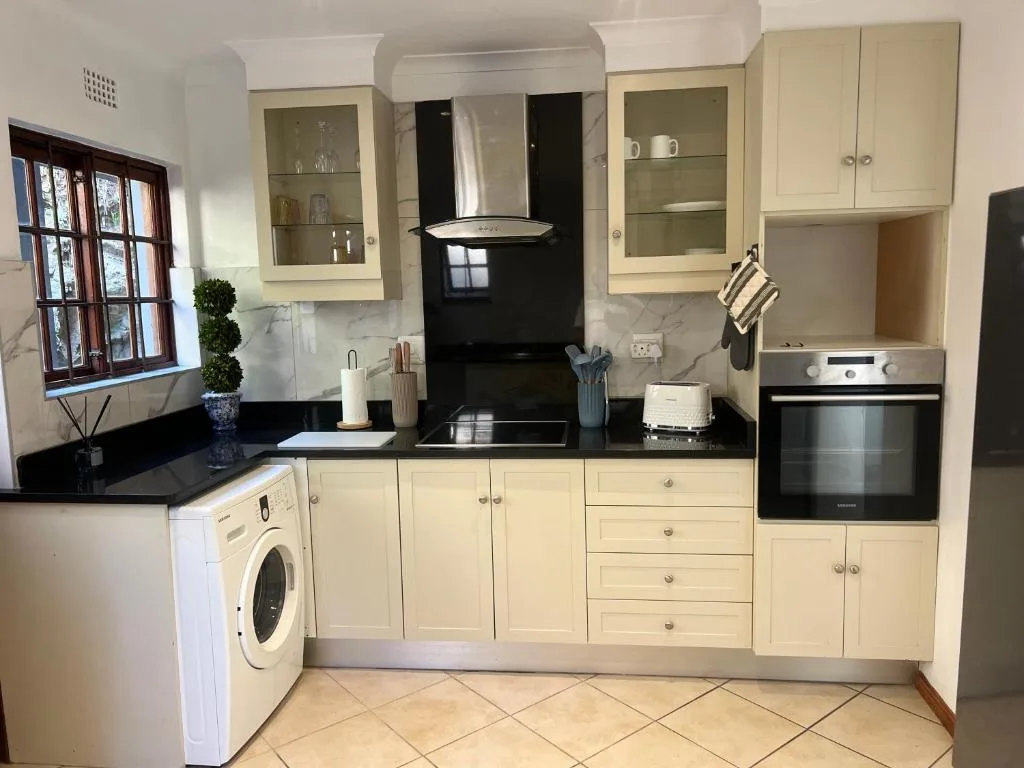 Cream cabinetry kitchen with black countertops, stove, and oven appliances