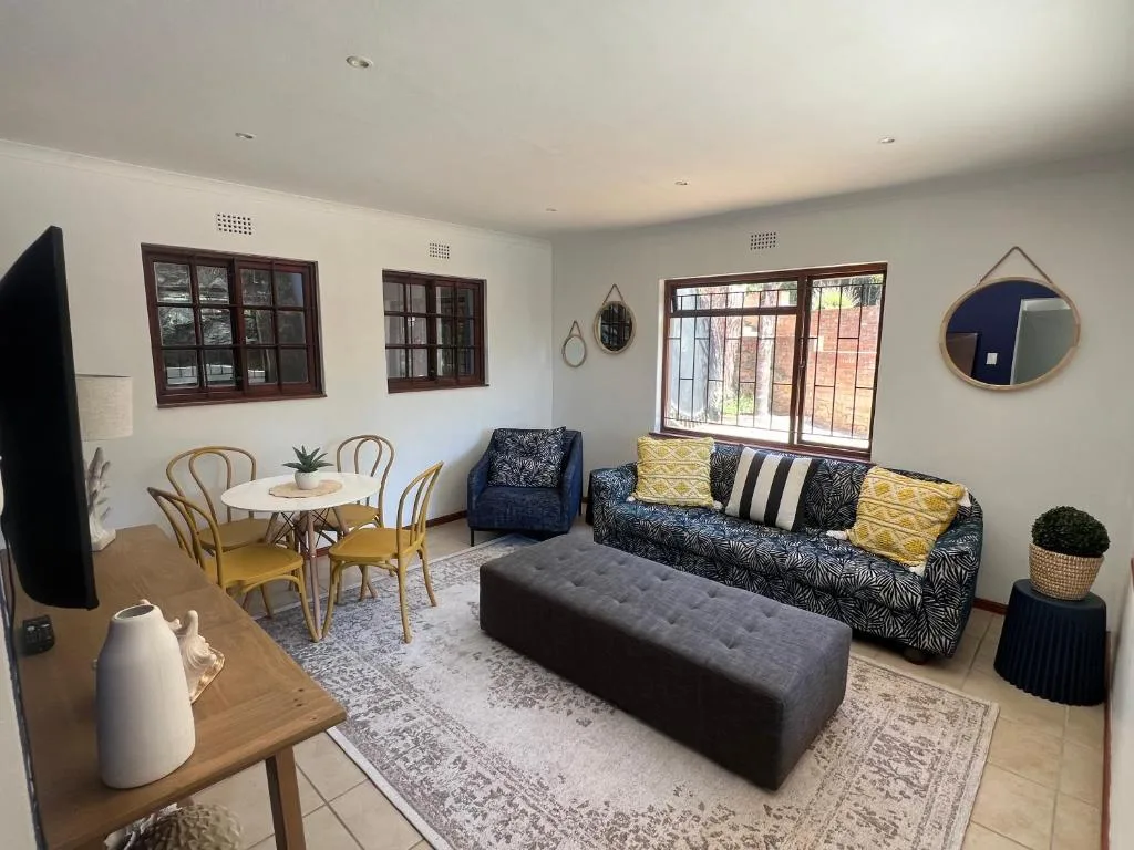 Bright open-plan lounge with patterned sofa, dining table, and large windows