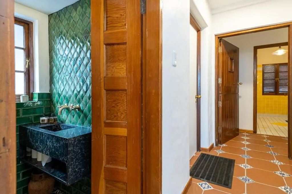 Bathroom with black marble sink vanity and green tile backsplash