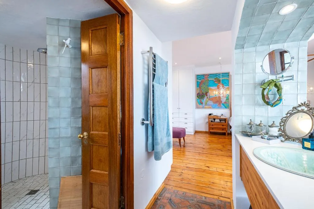 Spacious bathroom with walk-in shower, wooden door, and vanity sink