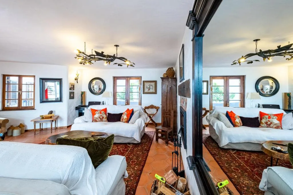 Spacious bedroom with multiple beds, orange pillows, and bright windows