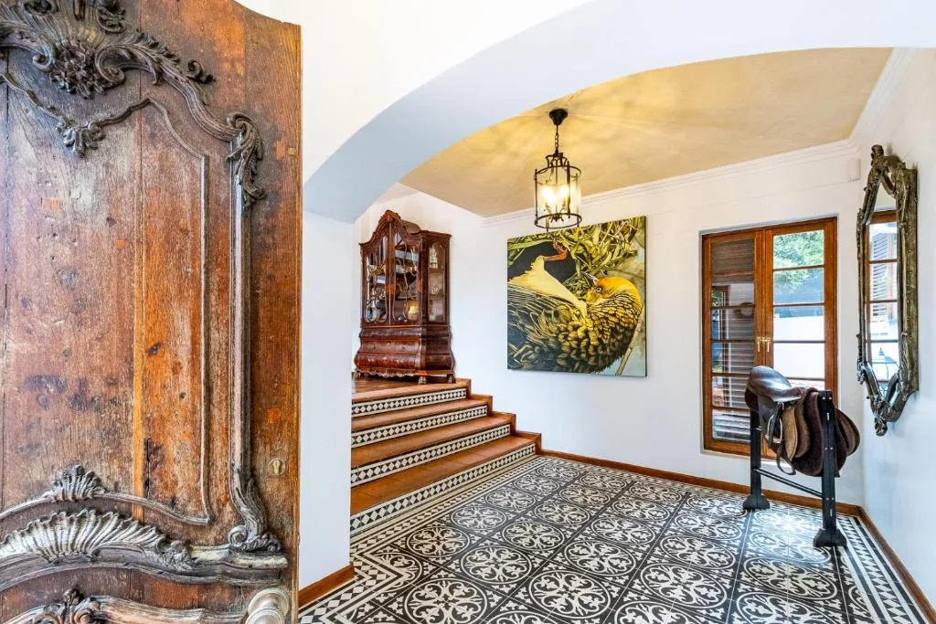Ornate entrance hall with decorative wooden door, patterned tiles, and artwork