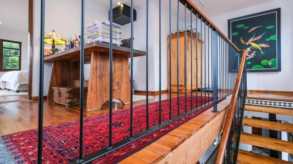 Interior loft space with wooden desk, red rug, and modern staircase railing
