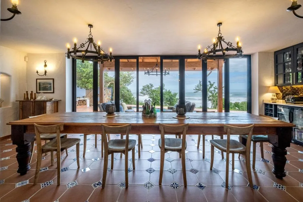 Elegant dining room with long wooden table overlooking ocean views