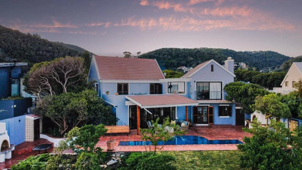 Blue and white villa with red tile roof, pool, and mountain views