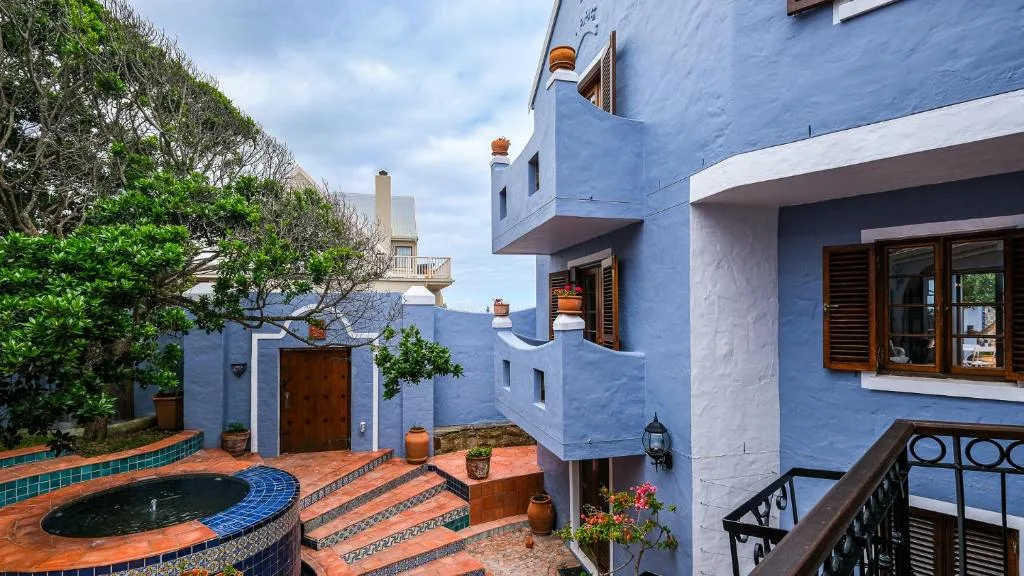 Vibrant blue villa with terracotta courtyard and small circular pool