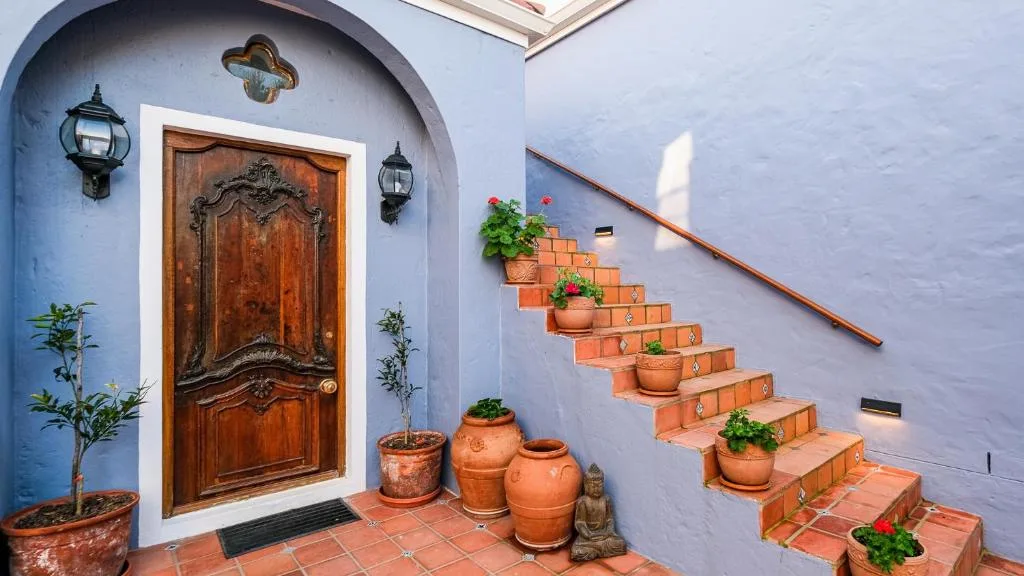Blue-painted villa entrance with ornate wooden door and decorative potted plants