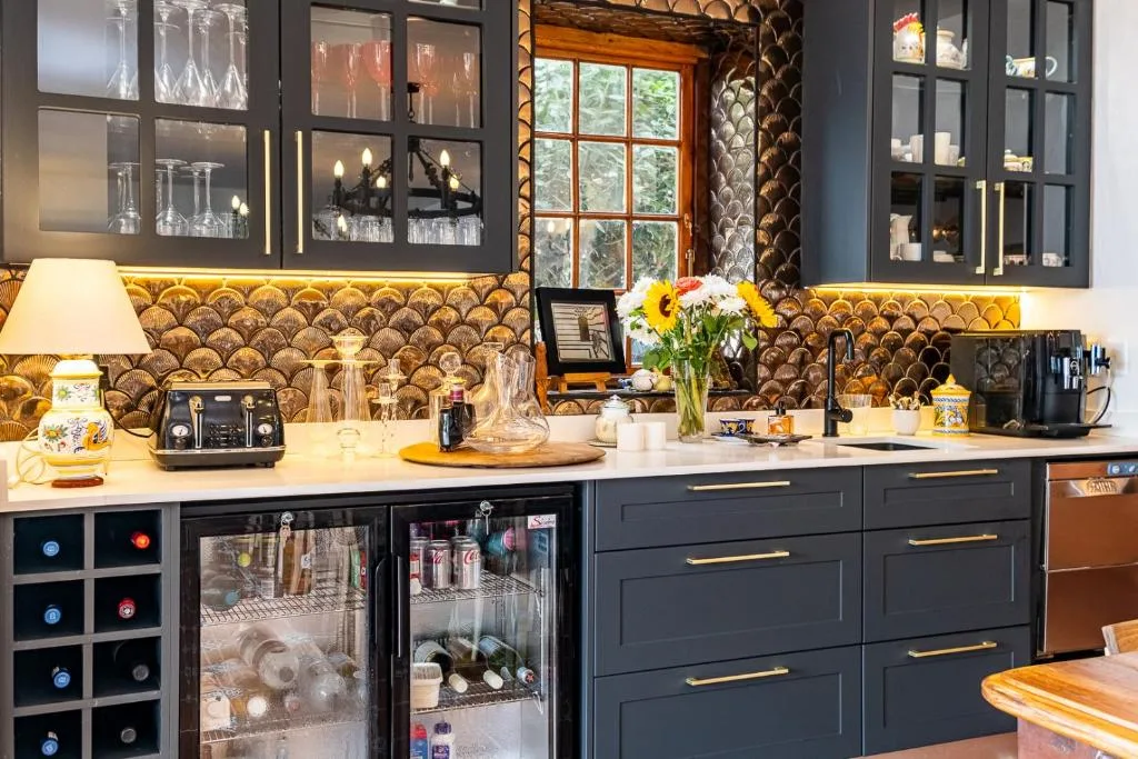 Modern kitchen with black cabinetry, gold backsplash, and fresh flowers on counter