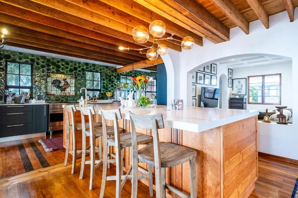Open-plan kitchen with island, dining seating, and exposed wooden beams
