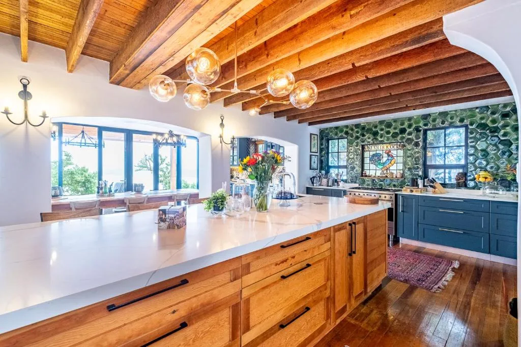 Spacious kitchen with wooden beams, island counter, and blue cabinetry