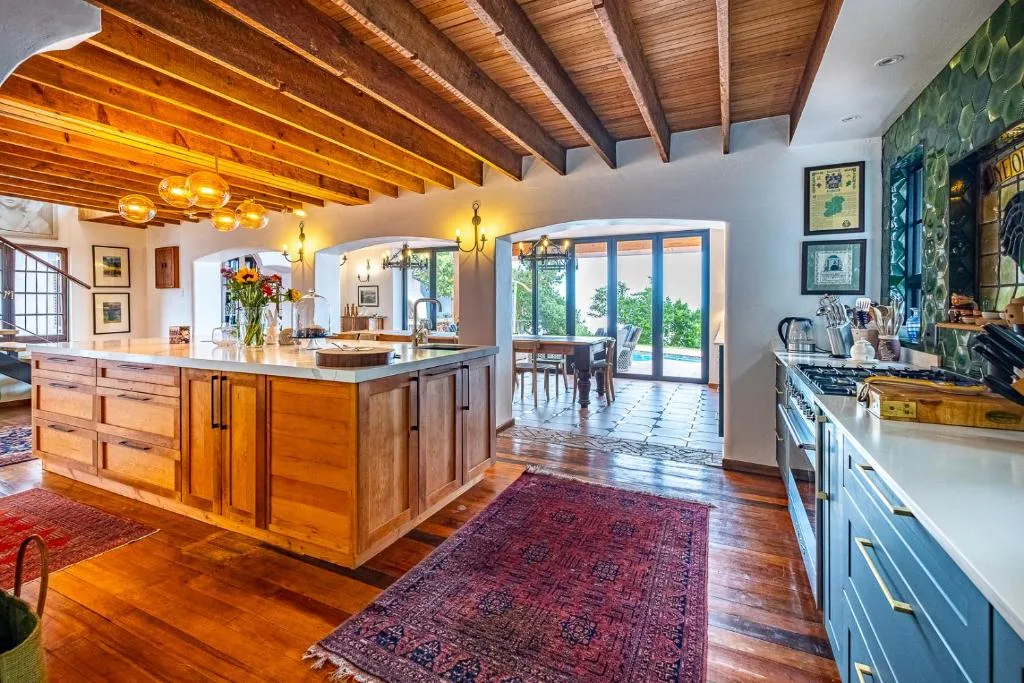 Spacious open-plan kitchen with wooden beams, island counter, and modern appliances