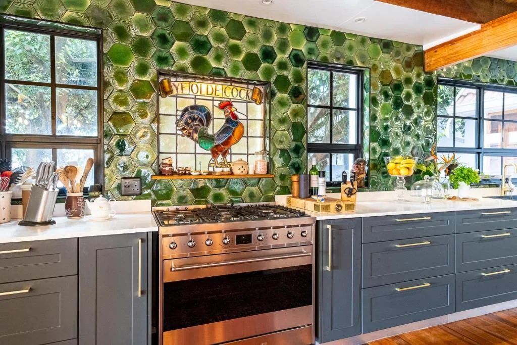 Modern kitchen with copper range cooker, green hexagonal tile backsplash, and rooster artwork