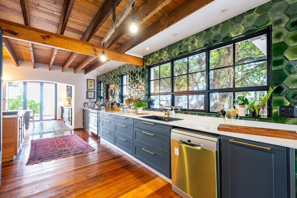 Modern kitchen with dark cabinetry, stainless steel appliances, and large windows overlooking garden