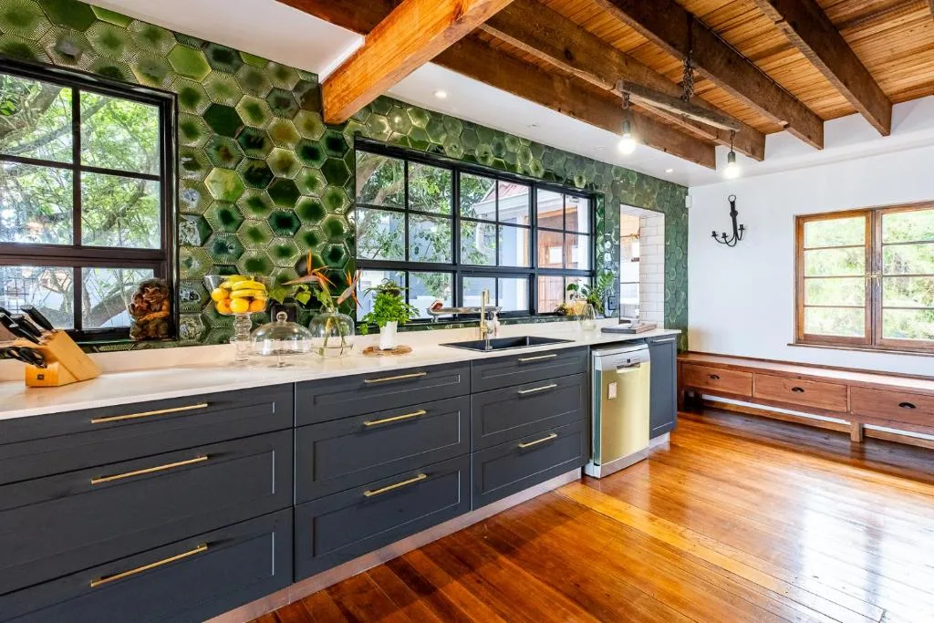 Modern kitchen with black cabinetry, white countertop, and large windows overlooking garden