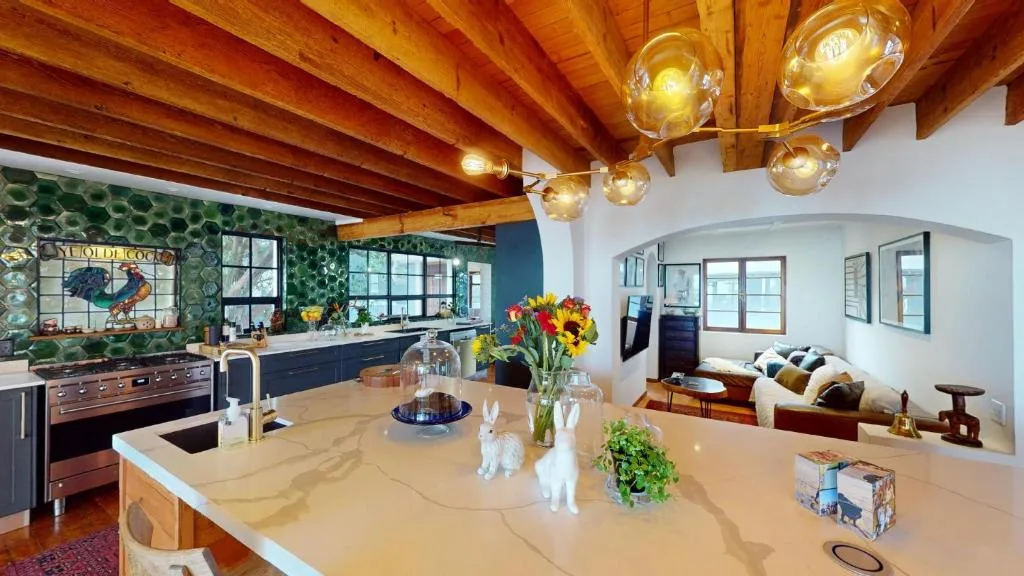 Open-plan kitchen with island counter, wooden beams, and modern appliances